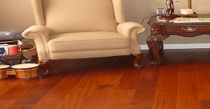 Cream armchair, dark wood table, and mahogany hardwood floor in a home setting.
