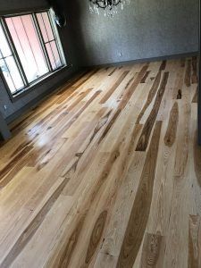 Light-colored hardwood floor with varying wood grain patterns in a room with a window.